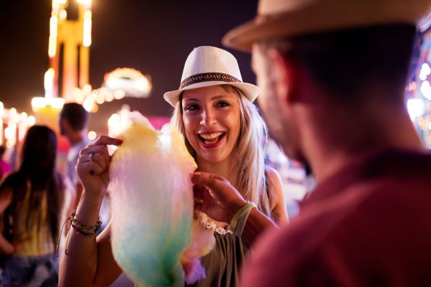 Man and woman at fair eating cotton candy together