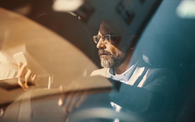 Man looking at phone while sitting inside car